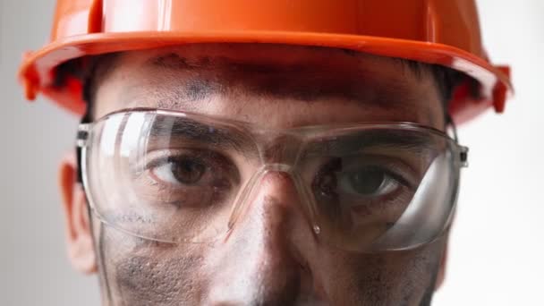 Retrato sucio cansado constructor masculino en el casco de trabajo y gafas se ve cámara — Vídeo de stock