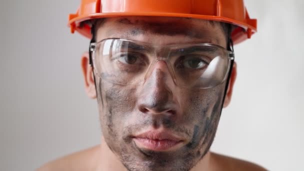 Portret brudny zmęczony budowniczy w kasku pracy i okulary wygląda aparat fotograficzny — Wideo stockowe