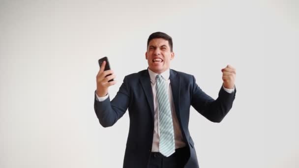 Счастливый офисный работник в формальной одежде пользуется мобильным телефоном, радуясь победе — стоковое видео