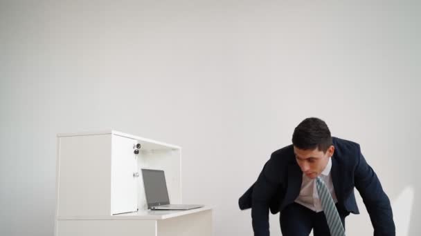Zakenman in formele kleding springt over bureau en gaat aan het werk op laptop — Stockvideo
