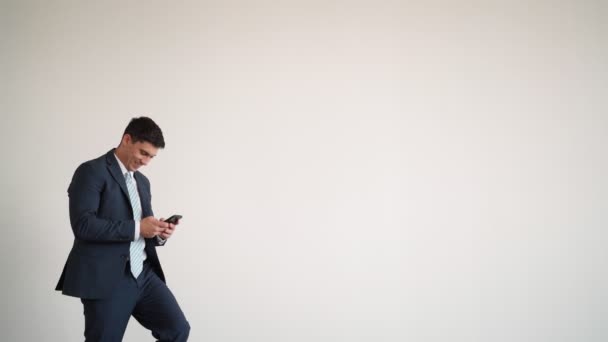 Obchodník v modré bundě a kravatu textování na telefonu klopýtne a komicky spadne — Stock video