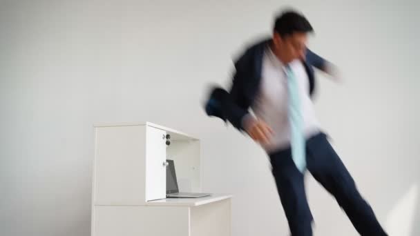 Hombre de negocios con ropa formal salta sobre el escritorio y se sienta a trabajar en el portátil — Vídeos de Stock