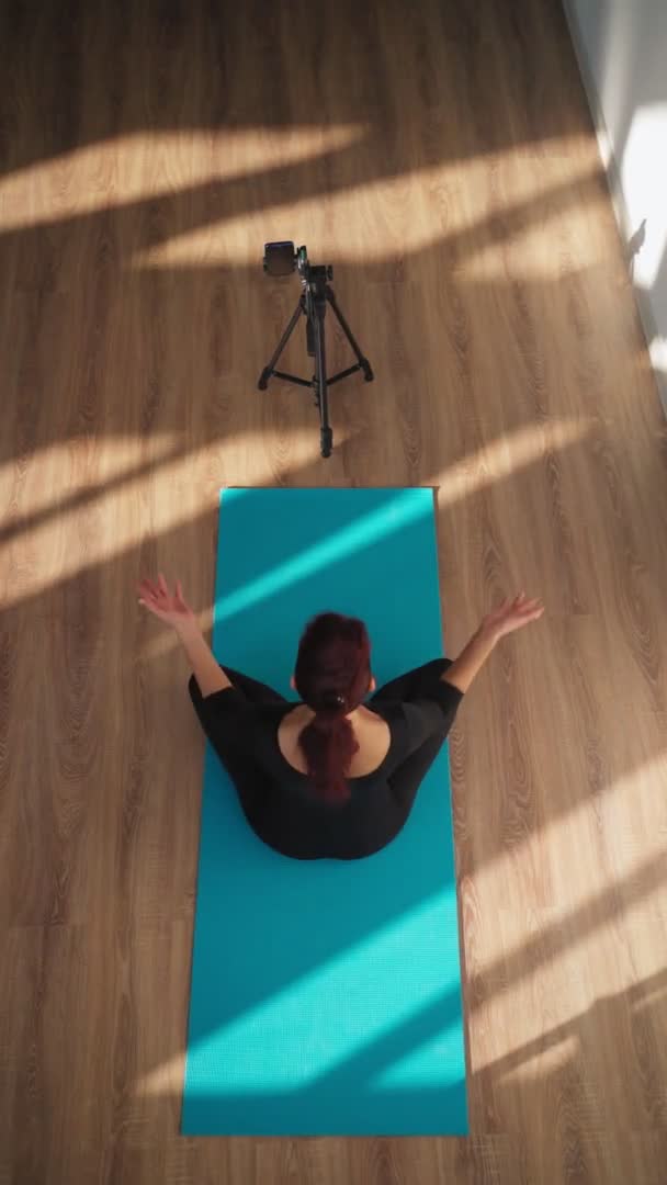 Mujer delgada está transmitiendo un entrenamiento en línea mediante la filmación de un video en su teléfono — Vídeos de Stock