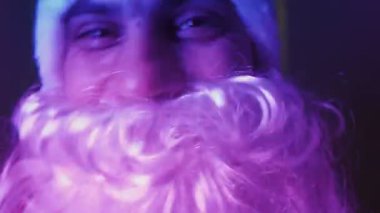 Neon ışıklı Noel Baba kostümlü mutlu adam evde tek başına dans ediyor.