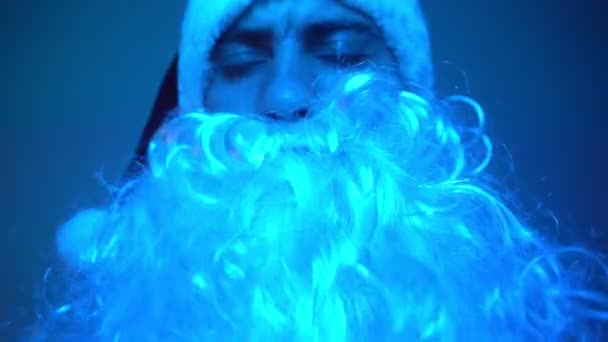 Щасливий хлопець в костюмі Санта-Клауса в неоновому освітленні танцює сам вдома — стокове відео