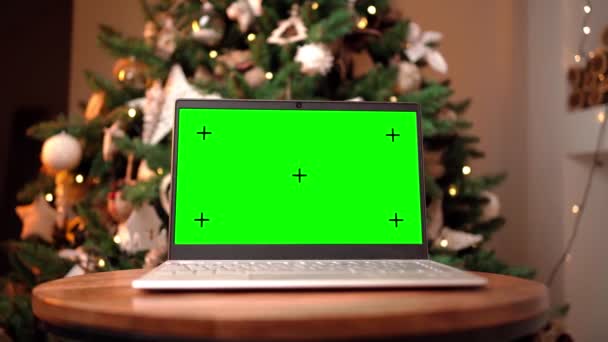 Φορητός υπολογιστής με πράσινη οθόνη και έγχρωμο κλειδί με φόντο ένα χριστουγεννιάτικο δέντρο — Αρχείο Βίντεο