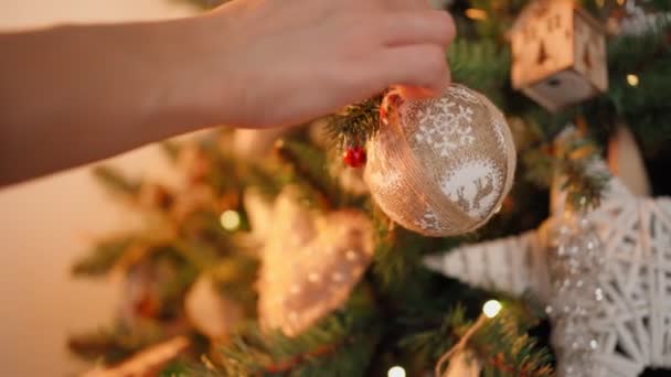 Mulher decora árvore de Natal com bolas festivas. Luzes quentes guirlandas Flicker — Vídeo de Stock