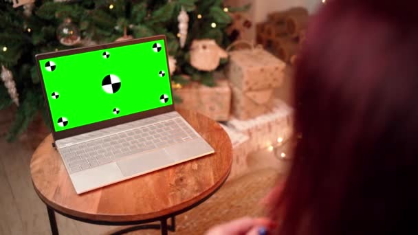 Žena v Vánocích komunikuje na video volání pomocí notebooku se zelenou obrazovkou. — Stock video
