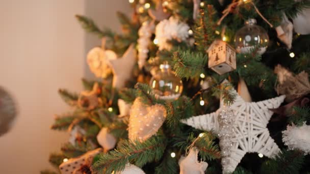 Menina decora árvore de Natal com bolas festivas. Luzes quentes guirlandas Flicker — Vídeo de Stock