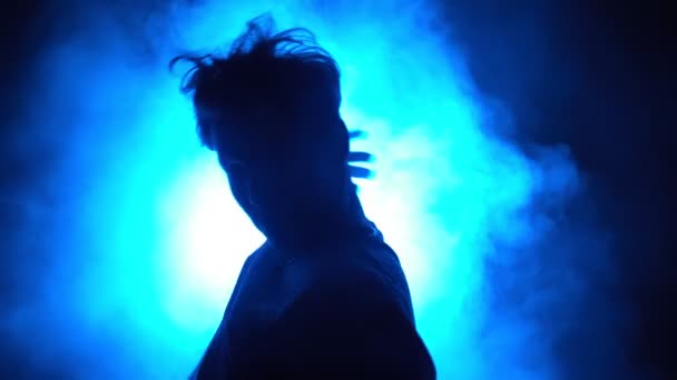 Silhouette, homme danseur de rue dansant dans une pièce enfumée avec lumière néon bleue — Video