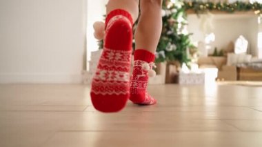 Kırmızı yılbaşı çoraplı kadın bacakları hediyelerle süslenmiş Noel ağacına koşar.