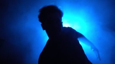 Siluet, erkek sokak dansçısı dumanlı odada dans ediyor.