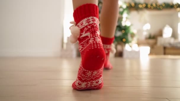 Счастливая женщина в красных новогодних носках бежит к украшенной елке с подарками — стоковое видео