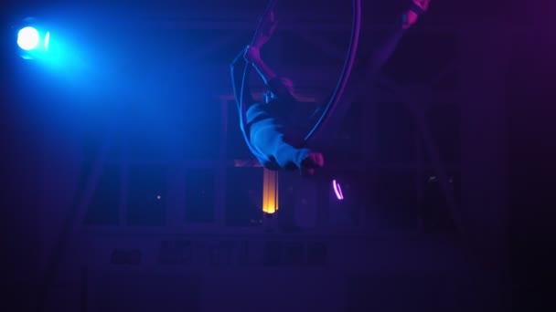 Sylwetka, gimnastyczka lotnicza wykonuje trik w ringu w zadymionym pomieszczeniu z podświetleniem — Wideo stockowe