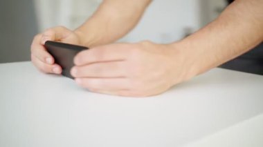 Yakın plan, bir adam masada dururken yeşil ekranlı akıllı telefon kullanır.