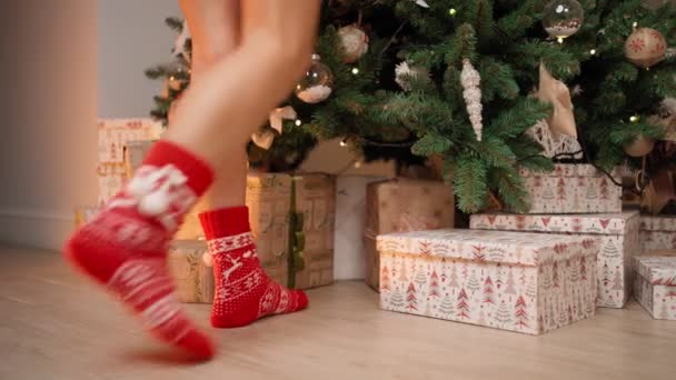 Donna in calzini rossi Capodanno arriva fino a punta di piedi per decorare l'albero di Natale — Video Stock
