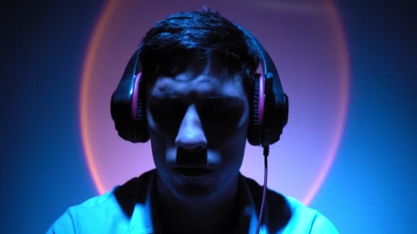 Портрет, человек расслабляет слушая музыку через наушники в неоновом освещении — стоковое видео