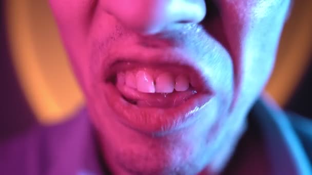 Close-up of a mans mouth screaming and swearing in neon lighting. Evil emotions — Stock Video