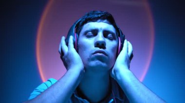 Portre, adam neon ışıkta kulaklıkla müzik dinleyerek rahatlıyor