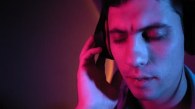 Portre, adam neon ışıkta kulaklıkla müzik dinleyerek rahatlıyor