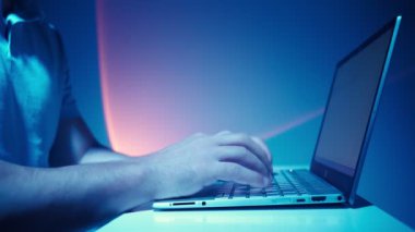 Adam Laptop 'ta çalışıyor. Kapalı mekanda nöroaydınlatma ve gelecekteki atmosfer. Bağımsız