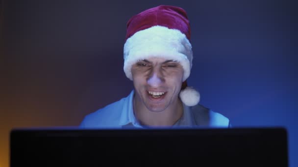 Felice uomo in cappello Babbo Natale sorride e comunica in videochiamata utilizzando il computer portatile — Video Stock