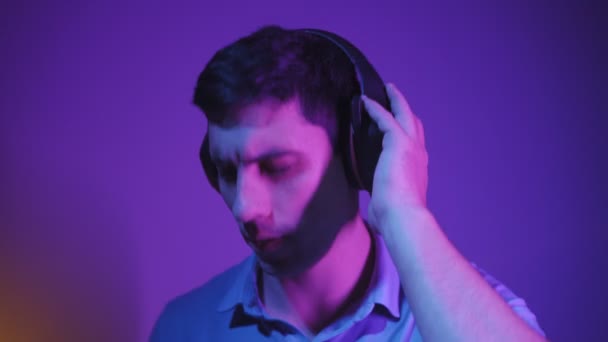 Portrait, l'homme détend l'écoute de la musique à travers des écouteurs dans l'éclairage au néon — Video