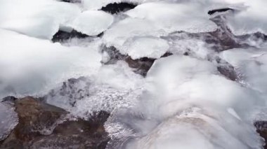 Kışın fırtınalı bir dağ nehri. Donmuş su ve buz. Yavaş çekim.