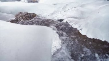 Kışın fırtınalı bir dağ nehri. Donmuş su ve buz. Yavaş çekim.