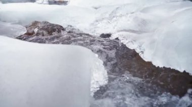 Kışın fırtınalı bir dağ nehri. Donmuş su ve buz. Yavaş çekim.