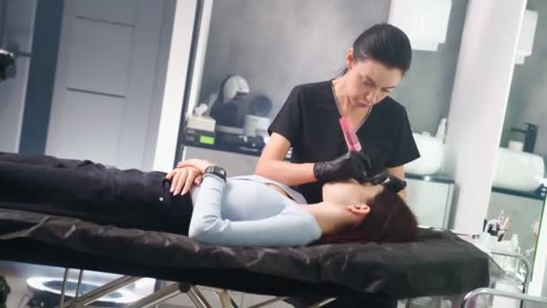 Guru membuat prosedur riasan alis permanen untuk wanita di salon kecantikan. — Stok Video
