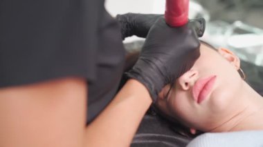 Usta güzellik salonundaki kadına kalıcı kaş makyajı yapıyor..