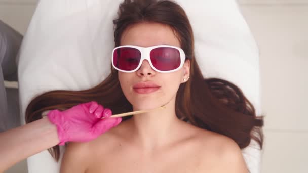 Cosmetologist faz a remoção de cabelo facial laser mulher bonita no salão de beleza — Vídeo de Stock