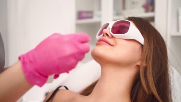 Cosmetologist faz a remoção de cabelo facial laser mulher bonita no salão de beleza — Vídeo de Stock