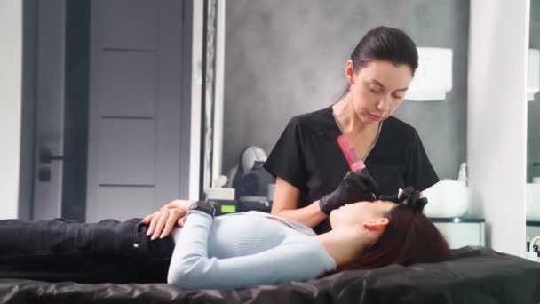 Мастер делает постоянную процедуру макияжа брови женщине в салоне красоты. — стоковое видео