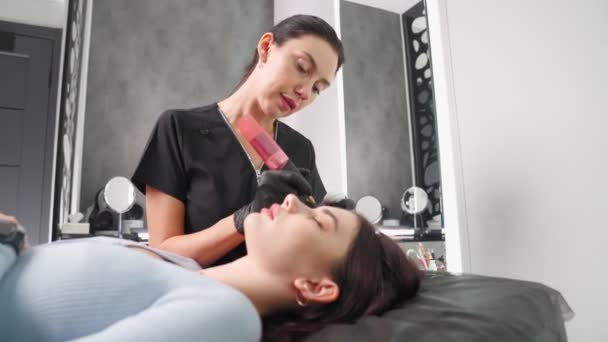 Мастер делает постоянную процедуру макияжа брови женщине в салоне красоты. — стоковое видео