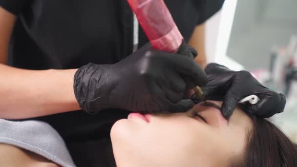 Master makes permanent eyebrow makeup procedure to woman in beauty salon. — Vídeo de Stock
