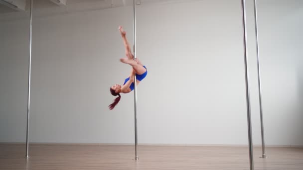 Athletic vrouw paal danser voert acrobatische stunts met stretching elementen — Stockvideo