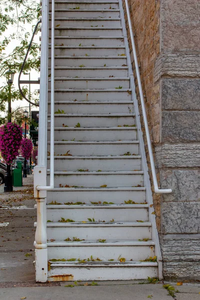 都会的な歩道の中にある魅力的な石造りの建物に沿って ヴィンテージの天気の良い白い塗装木製の階段のビューを閉じます — ストック写真