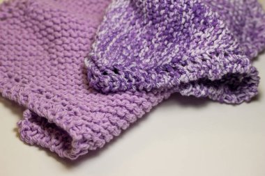 Bu resim, mor ve beyaz tonlarında, jartiyer dikişinde el örgüsü iplik kumaşının makro soyut bir arkaplanını gösteriyor..