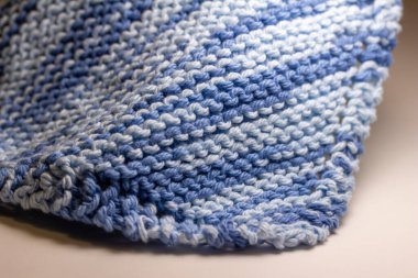 Bu resim, mavi ve beyaz tonlarında, basit bir jartiyer dikişinde el örgüsü iplik kumaşının makro soyut bir arkaplanını gösterir..