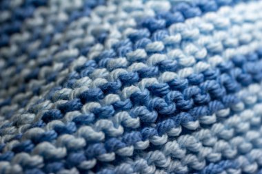 Bu resim, mavi ve beyaz tonlarında, basit bir jartiyer dikişinde el örgüsü iplik kumaşının makro soyut bir arkaplanını gösterir..