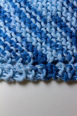 Bu resim, mavi ve beyaz tonlarında, basit bir jartiyer dikişinde el örgüsü iplik kumaşının makro soyut bir arkaplanını gösterir..