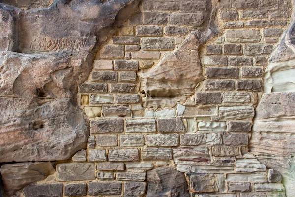この画像は 様々な場所でいくつかの近代的な修復と 古代の要塞化された石の壁の表面のユニークなテクスチャの背景ビューを示しています — ストック写真
