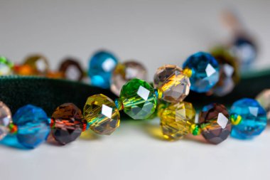Macro abstract texture background of a string of defocused colorful faceted glass beads on white background