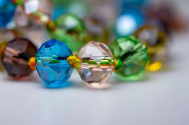Macro abstract texture background of a string of defocused colorful faceted glass beads on white background