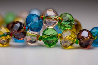 Macro abstract texture background of a string of defocused colorful faceted glass beads on white background