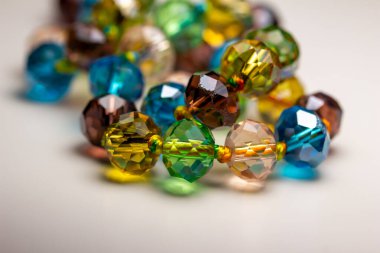 Macro abstract texture background of a string of defocused colorful faceted glass beads on white background