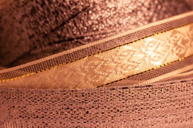 Full frame macro abstract texture background of shimmering fabric and metallic ribbon in a lovely shade of salmon pink