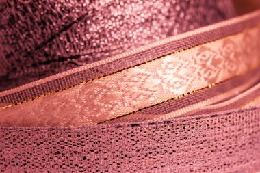 Full frame macro abstract texture background of shimmering fabric and metallic ribbon in a lovely shade of rosy pink